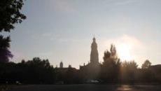 The sun rising up over the trees with the silhouette of the Chuch of the Immaculate Conception.